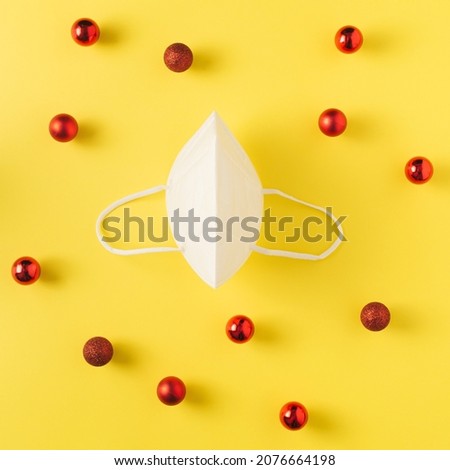Layout with protection mask and red New Year decorations on yellow background.