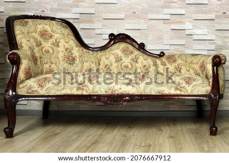 Antique furniture close-up. Sofa banquette in baroque style against the background of a wooden wall. Royalty-Free Stock Photo #2076667912