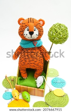 Handmade knitted soft toy. Amigurumi. Tiger toy with mice on the white background. Crochet stuffed animals. The toy is standing. Knitting and crocheting