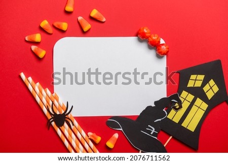 Blank paper sheet with candies and Halloween decor on red background