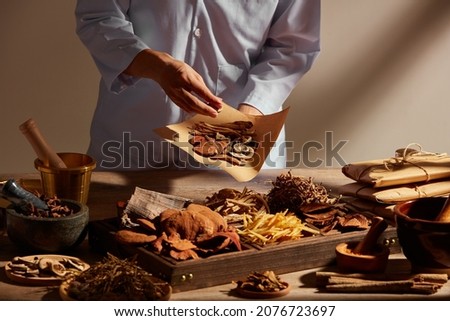 Traditional chinese medicine with herb and spices in brown wooden background mortar and pestile  , doctor holding a pack of medicine for advertising ,  traditional content 