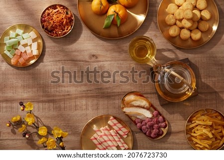 Happy lunar new year with mandarin orange teapot in golden dish candy jam , fried potato flower red pocket biscuit , wooden background photography Tet holiday content , chinese new year