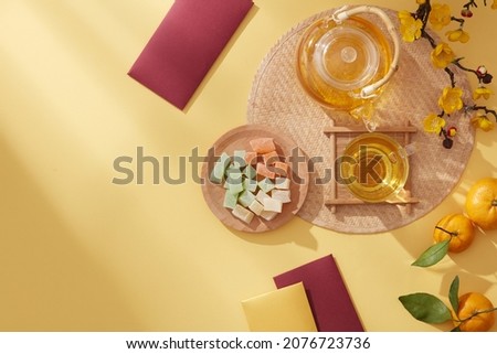 Chinese new year with mandarin orange teapot and candy , flower and red pocket , yellow background photography Tet holiday content , chinese new year , top view
