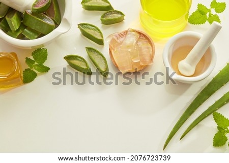 Aloe vera extract research in laboratory with yellow water in petri dish and a beaker mortar and pestle ,  green leaf in white background for aloe vera advertising , research content , top view 