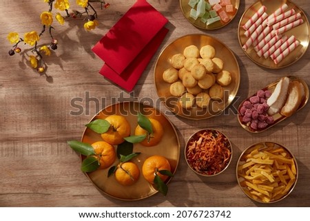 Happy lunar new year with mandarin orange teapot in golden dish candy jam , fried potato flower red pocket biscuit , wooden background photography Tet holiday content , chinese new year