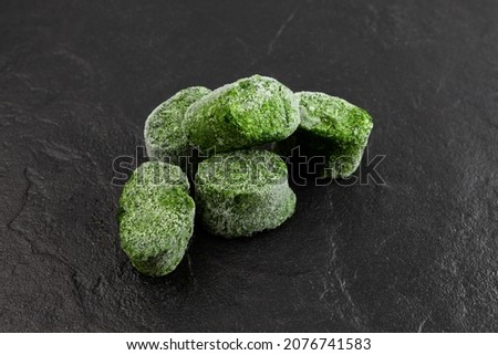 Crushed green spinach shock frozen in form of briquettes, selective focus. Food Reserve. Fresh frozen food. Smart solution for storing greenery.