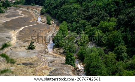 Environmental disaster. The polluted small local river is located next to the massive mining site in Serbia. Ecology problem caused by metallurgical industry.  Royalty-Free Stock Photo #2076742561