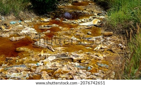 Environmental disaster. The polluted small local river is located next to the massive mining site in Serbia. Ecology problem caused by metallurgical industry.  Royalty-Free Stock Photo #2076742651