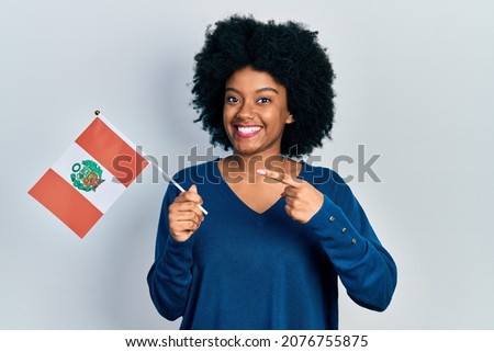Young african american woman holding peru flag smiling happy pointing with hand and finger 