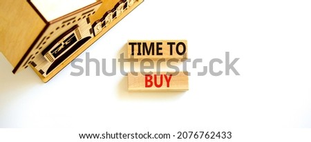 Time to buy house symbol. Concept words 'Time to buy' on wooden blocks near miniature house. Beautiful white background, copy space. Business and time to buy house concept.