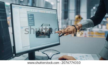 Two Automotive Engineers Discussing Concept Car Blueprints on Desktop Computer in Modern Office at Assembly Plant. Female Industrial Project Manager Talk to Male Designer at Vehicle Factory. Royalty-Free Stock Photo #2076774310