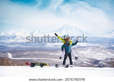 Cheerful couple with snowboards in front of snowy volcanos Royalty-Free Stock Photo #2076780598