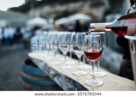 POURING RED WINE AT SOCIAL EVENT LIFE WEDDING PARTY OR OTHER LUXURY EVENT. Royalty-Free Stock Photo #2076785044