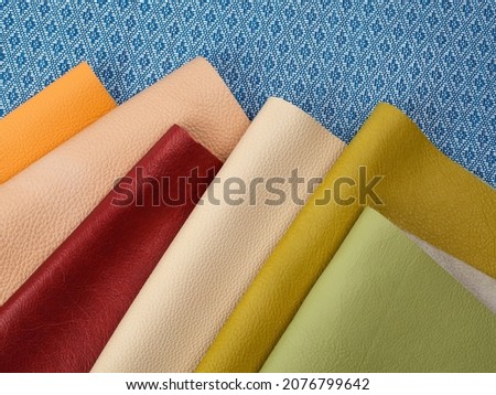 Different colors natural leather textures samples on blue fabric background