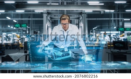 Confident Engineer Working on a New Electric Car with Use of Augmented Reality Hologram in an Office at Car Assembly Plant. Industrial Specialist Working in Technological Vehicle Development Facility. Royalty-Free Stock Photo #2076802216