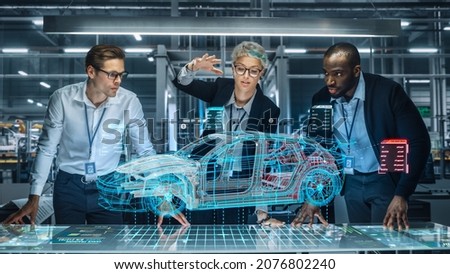 Diverse Team of Engineers Working in Office at Industrial Factory. Industrial Designers Discuss Electric Car Augmented Reality Hologramm. Specialists Work in Technological Car Development Facility.