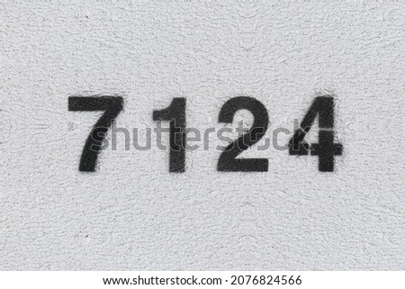 Black Number 7124 on the white wall. Spray paint. Number seven thousand one hundred and twenty four.