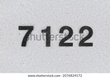 Black Number 7122 on the white wall. Spray paint. Number seven thousand one hundred and twenty two.