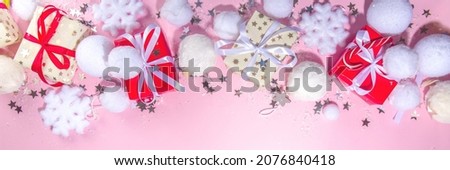 Fluffy Christmas concept. Festive Christmas background with fluffy decoration stuff, xmas ball, gift boxes, with artificial snow and shiny stars on pink color background copy space