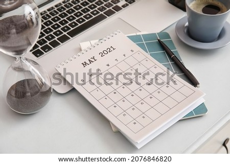 Flip paper calendar with laptop, hourglass and stationery on table