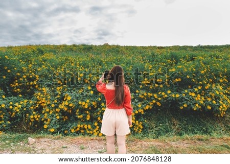 Young Asian woman taking selfie with mobile smartphone in the flower garden