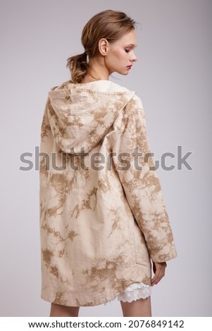 High fashion photo of a beautiful elegant young woman in a pretty jacket with beige streaks,  posing over white background. Slim figure. Studio shot