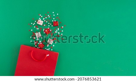 Paper bag with Christmas decorations, gift boxes, confetti. Holiday shopping and sale concept. 