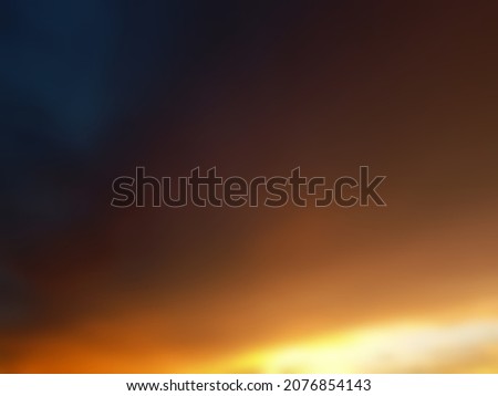 Defocused abstract background of orange evening sky with blue dark side