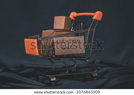 Close up photo of cardboard boxes with message christmas sale writen over supermarket shopping cart. Studio shot isolated on dark green background.