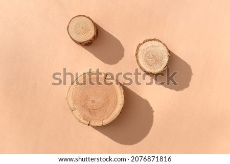 Three wooden disks lying on a trendy beige background. A platform made of trees for luxury and natural cosmetics or products presentation. Wood tray mockup in the sunlight. Top view