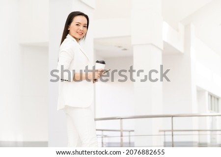 Portrait Of Successful A middle-aged Asian businesswoman Holding smart phone and coffee smiling to camera