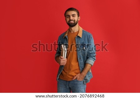Happy student with books on red background