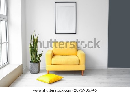 Interior of modern stylish room with armchair and blank photo frame