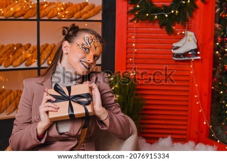 
A beautiful girl with a tiger make-up rejoices at the gift. New year concept. Year of the tiger