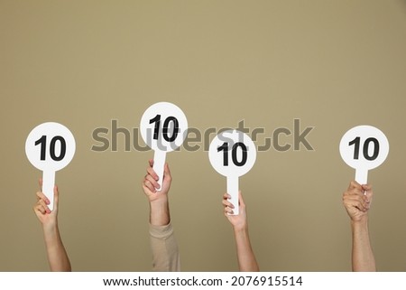 Panel of judges holding signs with highest score on beige background, closeup Royalty-Free Stock Photo #2076915514