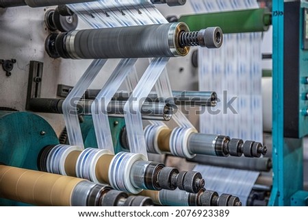 Rotary die cutting machine with slitting blade system. Production of duct tape.Packing tape manufacturing. Modern machine for packaging line in factory, Industrial and technology concept. Royalty-Free Stock Photo #2076923389