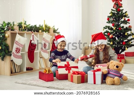 Overjoyed small boy and girl kids have fun unpack wrapped boxes with presents on Christmas morning. Happy little children open unbox packages on New Year. Winter holiday celebration concept.