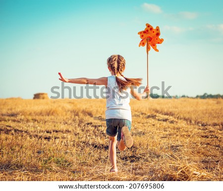 cute little girl in summer day holds windmill in hand Royalty-Free Stock Photo #207695806
