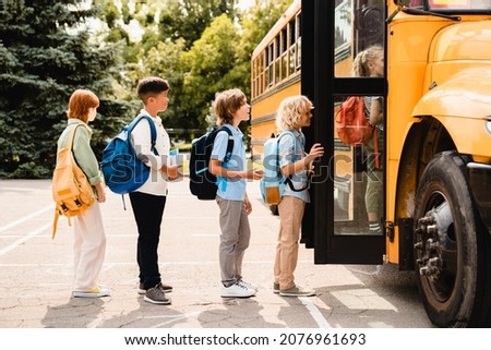 Multiethnic pupils classmates schoolchildren students standing in line waiting for boarding school bus before starting new educational semester year after summer holidays Royalty-Free Stock Photo #2076961693