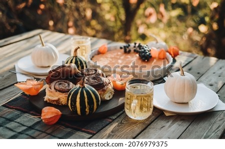 Thanksgiving festive table. Autumn style table setting with pumpkins, leaves and physalis. Pumpkin pie and cinnamon rolls. Cozy autumn scene. Flat lay. Fall styled composition.