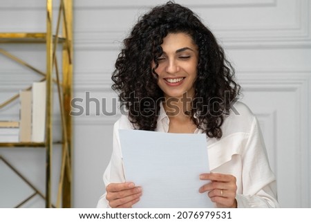 Happy ethnic woman with curly black hair reads a letter with good news, a great offer, an opportunity to get a job Royalty-Free Stock Photo #2076979531