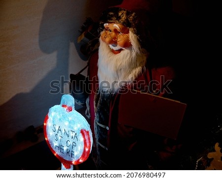 Toy Santa Claus stands near the Santa sign stops here. High quality photo