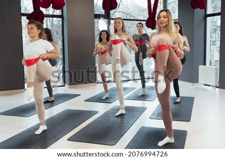 Ribbon exercises. Group of young sportive girls in sportswear training together, stretching at yoga meditation center. Concept of healthy lifestyle, sport, wellness, wellbeing, mental health.