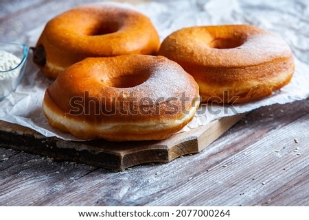 Delicious donuts with powdered sugar on wooden table.