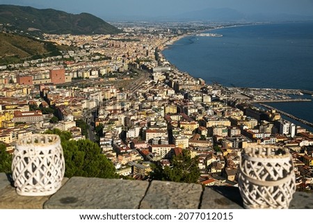 View of the city of Salerno from above with some candle holders in the foreground out of focus-Italy