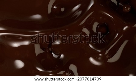 Closeup of splashing dark melted chocolate, top view.