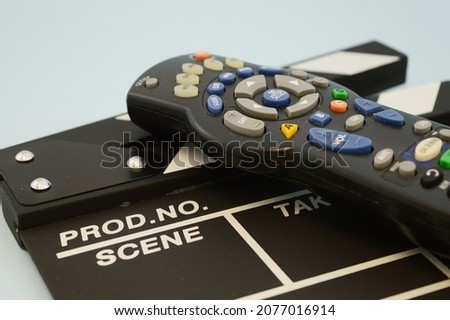 A remote controller ontop of a clapperboard for concepts in the show business industry.