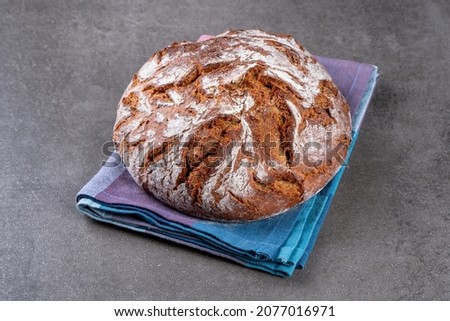 Traditional wholemeal rye bread in country style. Single object on a checkered napkin. Top view, copy space. Royalty-Free Stock Photo #2077016971