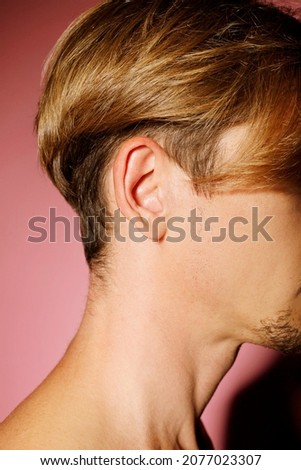 Close up picture of man ear over pink background. Ear health concept.