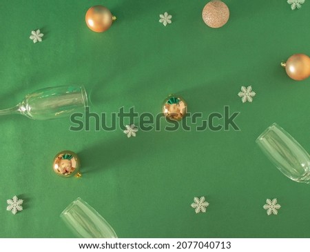 pattern made with golden baubles, white snowflakes and champagne glass on the pastel green table. Retro modern creative decoration with copy space